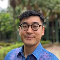 Man in glasses and buttoned up shirt in lush walkway